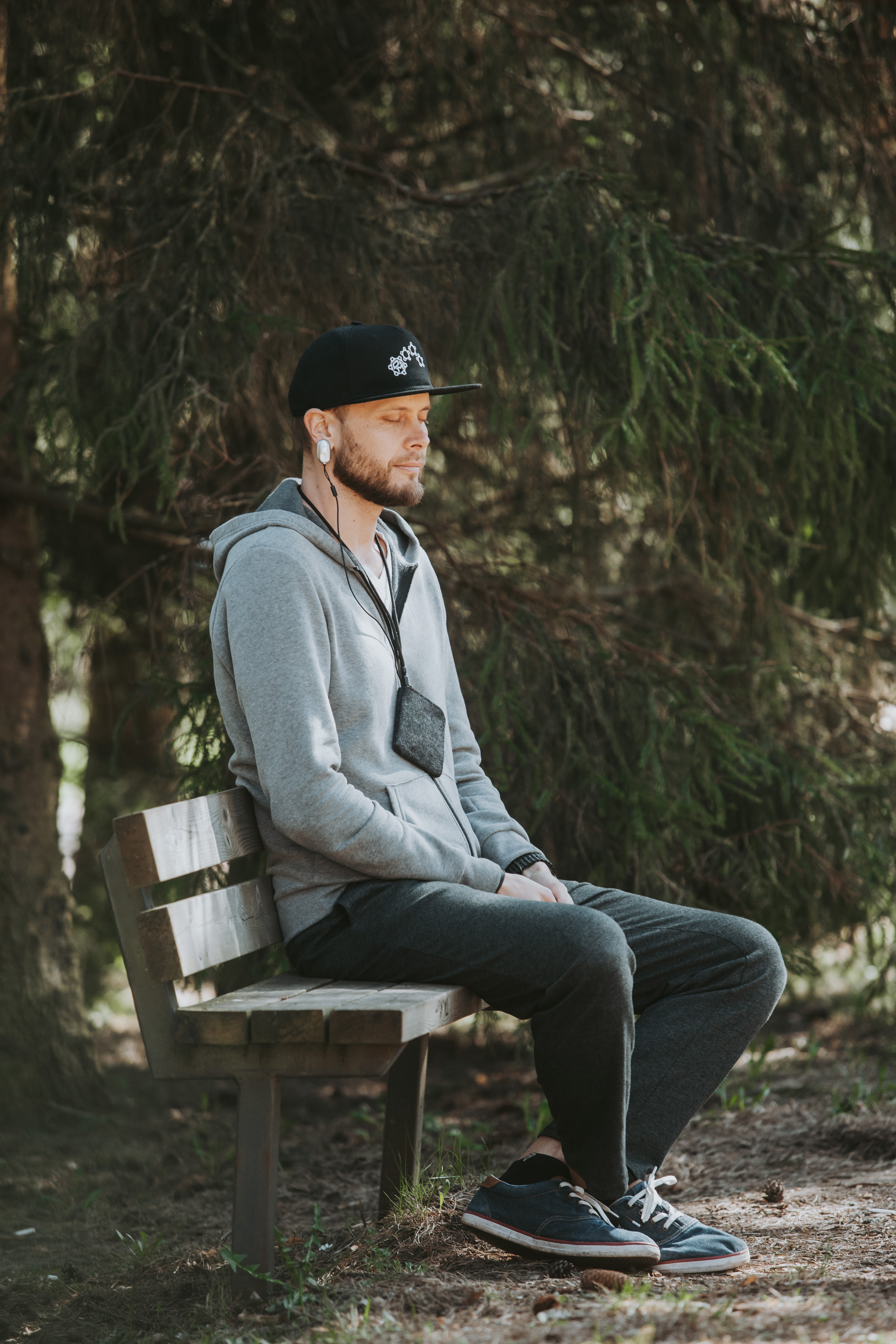 Martin Hoolma istub metsa all pingil silmad suletud, kõrva küljes HeartMath sensor.